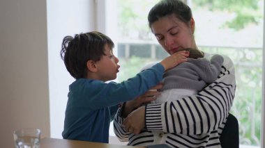 Anne hem yeni doğan hem de büyük çocuğunu yanında tutarak aile içinde paylaşılan sıcaklığı, sevgiyi ve bağlantıyı vurgulayan samimi ve huzurlu bir aile anı yaratıyor.