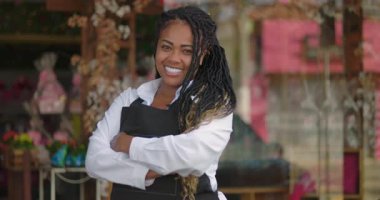 Çiçekçi dükkanının önünde kollarını kavuşturup gülümseyen, çiçeklerle ve dekorasyonlarla dolu yaratıcı mağazaların önünde gurur ve neşe saçan biri.