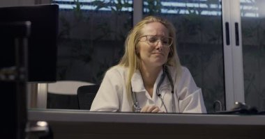 Kadın doktor umutsuzca başını eğiyor. Gece klinikte şiddetli yorgunluk belirtileri gösteriyor.