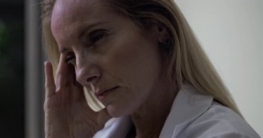 Kadın doktorun sinagogda el ele dinlenirken, gözleri duygusal yorgunluk anında kapalı klinik ortamında.