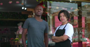 Çiçekçiler çiçek butiğinin önünde ciddi ifadelerle yan yana duruyorlar, kentsel perakende sektöründe profesyonellik ve güç taşıyorlar.