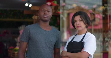 Çiçekçinin önünde ciddi yüz ifadeleriyle duran iki çiçekçiye yaklaş. Bağımsız iş ortamında güven ve birlik ifade ediyorlar.