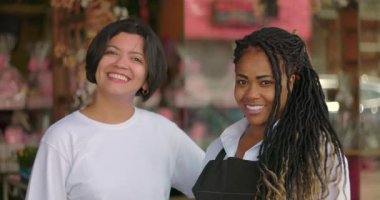 Çiçekçi dükkanının önünde duran gülümseyen iş ortakları çiçeklerle süslenmiş bir mağazanın önünde güven ve dostluk gösteriyorlar.