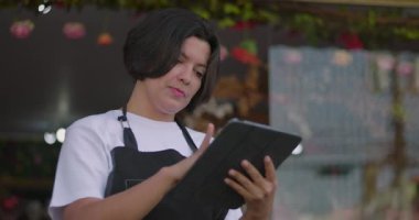 Çiçekçi, çiçekçi dükkanının önündeki tabletle konuşurken nazikçe gülümsüyor. Çiçekçide sıradan bir dijital bağlanma anı.