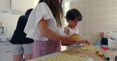 Mutfakta para kazanan kardeşlerin yakın çekimi, kız ve oğlan aşçılık işine odaklandı, aile yemekleri aktivitesi, anne arka planda, takım çalışması, bağ kurma, parlak mutfak