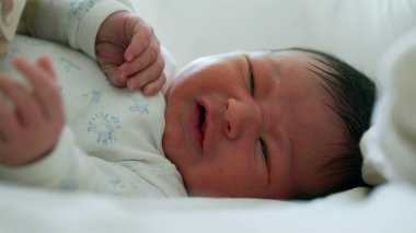 Yeni doğan bebeğin gözleri açık somurtması, hayatın ilk ayı boyunca ilk ifadeleri ve hareketleri, bebeklik, gelişme ve yeni hayatın başlangıcını gösteriyor.