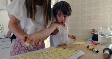Mutfakta para kazanan kardeşlerin yakın çekimi, kız ve oğlan aşçılık işine odaklandı, aile yemekleri aktivitesi, anne arka planda, takım çalışması, bağ kurma, parlak mutfak