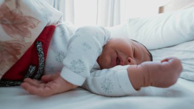 Yeni doğmuş bir bebeğin kollarını ve ellerini uzatarak uyuduğu ilk çocukluk sükunetini yakaladığı yakın plan.