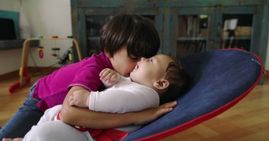 Büyük kardeş, bir fedainin üzerindeki küçük kardeşle şefkatle iletişim kuruyor. Bir yuva ortamında aralarındaki güçlü bağı ve sevgiyi vurgulayan dokunaklı ve sevgi dolu bir an yaratıyor.