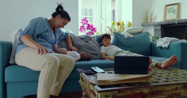 Anne, güneşli bir oturma odasında bebeğine gülümserken anne ve çocuk arasında sıcak ve sevgi dolu bir bağ kuruyor.