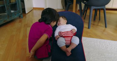 Büyük kardeş, bir fedainin içindeki küçük kardeşle etkileşime girmek için eğiliyor, aralarında hassas ve sevgi dolu bir anı vurguluyor, bir yuva ortamında çocukluğun masumiyetini ve neşesini yakalıyor.