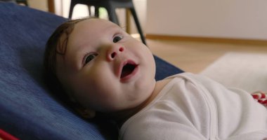 Bebek bir fedaide yatar, düşünceli bakar ve görünür, rahat bir ev ortamında bir anlık sakinlik ve yansıma yakalar, çocukluk zamanının masumiyetini ve huzurunu gösterir.