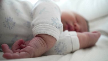 Yeni doğmuş bir bebeğin yakın planda uyuması eline odaklanır, çocukluk döneminin hassas ve hassas detaylarını huzurlu bir ortamda yakalar.