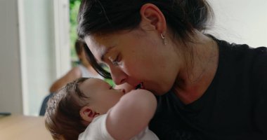 Anne ve bebek yoğun bir bakışı paylaşıyor, aralarındaki derin duygusal bağı ve bağı vurguluyor, yuva ortamında samimi ve samimi bir aile anı yaratıyor.