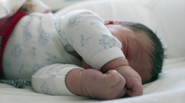 Yeni doğan bebek kıvrılıp uyuyor. Rahat ve güvenli bir ortamda çocukluğunun huzurunu ve huzurunu vurguluyor.