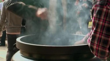 Kültürel dönüm noktasındaki geleneksel arındırma ayini sırasında tütsü çubuklarını tütsü ocağının üzerine yakın plan.