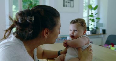 Anne bebeğine sıkıca sarılıyor. İkisi de hassas bir anda. Sıcak bir evin penceresinden süzülen doğal ışıkla.