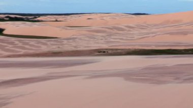 Kum tepeleri ufuk boyunca uzanıyor, geniş gökyüzünün altında rüzgarla oyulmuş desenlerle süslenmiş, sürekli değişen çöl manzarasını resmediyor.