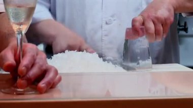 Şef, Japon mutfağındaki bir tezgahta özel uyumu olan bir buz bardağı oluşturmak için bir bıçakla buzu oyup bardağın etrafına şekil vererek eşsiz bir yemek hazırlıyor.
