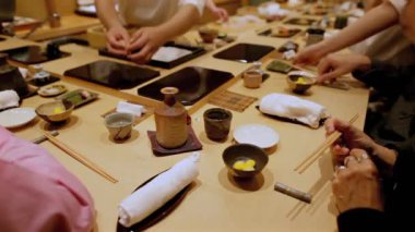 Geleneksel Japon yemeği sırasında seramik sake şişesi, çiğ bıldırcın yumurtası, küçük tabaklar ve çubuklarla zarif bir masa düzeni.
