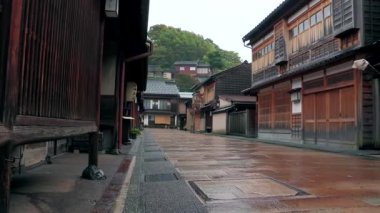 Kanazawa, JAPONYA, 17 Kasım 2010 - Yağmurla ıslanmış taş cadde, bank ve kağıt fener boyunca geleneksel ahşap binalar, arka planda dağ evleri olan sakin tarihi bölge