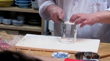 Şef, geniş buz silindirini geleneksel Japon tekniğini kullanarak sivri bardağa dönüştürür. Cam ise kesme tahtasına sıkıca tutunur.