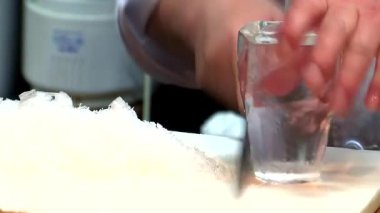 Karmaşık aşçılık sürecinde kalın donmuş bir bloğu içinde camla dilimleyerek özel buz bardağını şekillendiren ellerin yakınlaştırılması