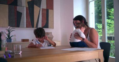 Masada evde eğitim görürken gözünü ovuşturan yorgun çocuk, yanında bebeğini kucağında tutan anne, aile dinamiklerini ve eğitim odaklarını ön plana çıkarıyor.