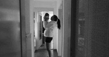 Anne bebeğini loş bir koridorda neşeli ve şefkatli bir anı paylaşarak kaldırıyor. Siyah ve beyaz ayarı duygusal bağlarını ve bağlantılarının basitliğini vurgular.