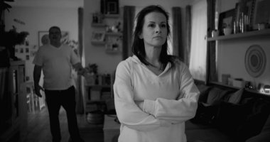 Şiddetli tartışmalar sırasında sert ifadeli bir kadının yakın çekimi, arka planda bulanık bir adam öfkeyle işaret ediyor, duygusal gerilimi yakalıyor ve çözülmemiş çatışmaları yakalıyor.