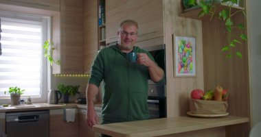 Sıcak içeceğe, kahveye ya da çaya tepki veren bir adam. Düşünce anı, gündelik mutfak düzeni, modern iç mekan, ev içi aktiviteler, evde kişisel zaman geçirme.