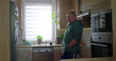 Modern mutfakta duran adam, düşünceli poz, gündelik yaşam tarzı, elleri cepte, huzurlu ev düzeni, doğal ışık ile ev rutini