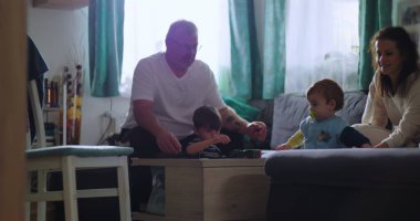 Baba ve çocuklar masanın etrafında toplandı. Genç çocuk öne doğru eğilirken, anne sıcak ve çekici aile anlarında gülümsüyordu.