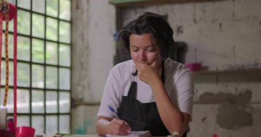 Çiçekçi kadın, kırsal kesimdeki çiçekçinin çalışma tezgahını planlarken, küçük işletme sahibinin girişimci güçlüklerle karşı karşıya olduğunu düşünüyor