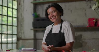 Kırsal kesimdeki çiçekçide gülümseyen kadın çiçekçi, küçük işletme sahibi, çiçekçilik sektöründe yaratıcı bir kariyer için kendini emin ve pozitif hissediyor.