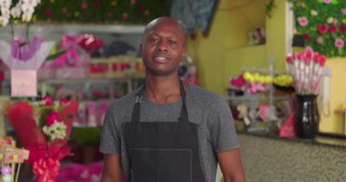 Çiçekçinin içinde ciddi bir şekilde duran çiçekçi, renkli çiçeklerin, buketlerin ve canlı hediyelerin arasında poz veren küçük bir işletme sahibi.