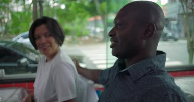 Restorandaki farklı arkadaşlar arasında neşeli bir an, Afrikalı Amerikalı bir adam şaka olsun diye kollarını Latin bir kadına doladı.