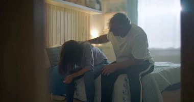 Kocası üzgün karısına destek oluyor, yatağın kenarında oturuyor, duygusal mücadeleye odaklanıyor, zihinsel sağlık farkındalığı, umutsuzluk, üzüntü ve kişisel kriz temaları