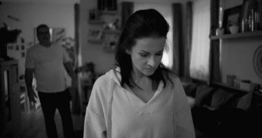 Kadın hararetli tartışmalar sırasında yüzünü geri çeviriyor. Arka plandaki adam duygusal hareketler yapıyor. Gerilime ve gergin ilişki dinamiklerine odaklanıyor.