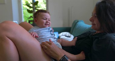 Anne bebekle kanepede uzanıyor, huzurlu bir evde dinleniyor, sıcak ve rahat bir oturma odasında sessiz bir bağ kurma zamanını paylaşıyor.