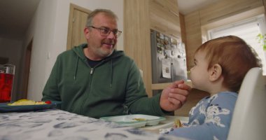 Babam gülümseyerek ve karnını doyurarak sandalyeye oturmuş, sıcak bir ev mutfağında yemek masasında eğlenceli bir ilişkiye giriyordu.