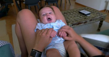 Anne kucağında bebekle oynuyor. Sıcak bir ev ortamında birlikte eğleniyor ve gülüyor. Aile bağlarının sıcaklığı.