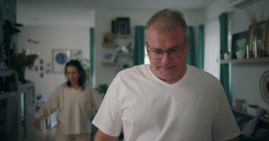 Erkek, tartışma sırasında yoğun bir ifadeyle kameraya bakıyor, kadın oturma odasında, gergin ve duygusal bir ilişki çatışması ve hüsran anı yaşıyor..