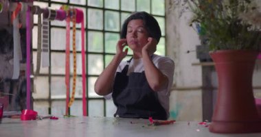 Çiçekçi kadın boynunu uzatıyor ve kırsal çiçekçide çalıştıktan sonra dinleniyor. Küçük işletme sahibi yoğun iş gününden sonra dinlenmek için mola veriyor.