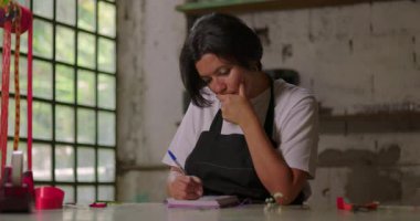 Kırsal kesimdeki çiçekçide yazan ve hayal kuran kadın, küçük işletme sahibi gelecek planları ve yeni fırsatlar hakkında yaratıcı düşünüyor.