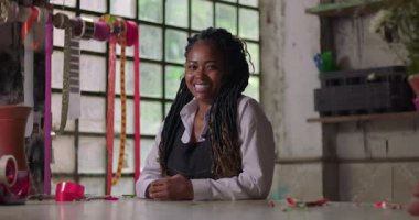 Kırsal bir çiçekçide işten sonra gururla gülümseyen bayan çiçekçi, küçük işletme sahibi zorlu bir günden sonra direnç ve pozitif tavır sergiliyor.