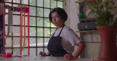 Kır çiçekçisinin tezgahında kendinden emin duran bayan çiçekçi, yaratıcı çalışma alanında azimle poz veren küçük işletme sahibi.