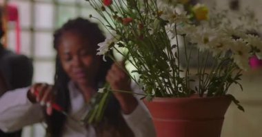 Çiçekçi kadın çiçekçi, kırsal çiçekçi dükkanında dikkatlice buket düzenliyor. Çiçek tasarımı ve müşteri hizmetleri hazırlıklarına odaklanan yaratıcı küçük işletme sahibi.