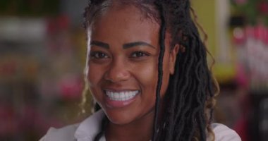 Gülümseyen neşeli Afro-Amerikan çiçekçinin yakın portresi. Çiçekçide kendine güveni tam bir ifade.