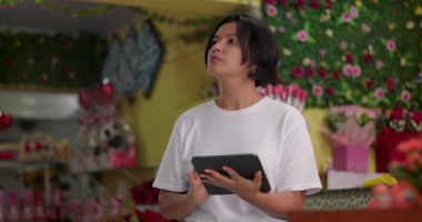 Çiçekçi dükkanının planlarını düşünürken tablet kullanan kadın çiçekçi, rahat ve odaklanmış duruş